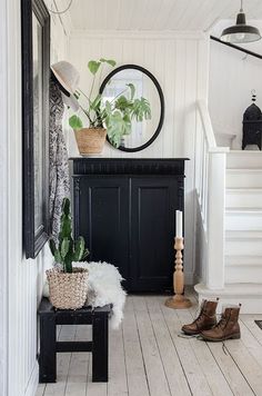 a room with white walls and wooden flooring, a black cabinet in the corner