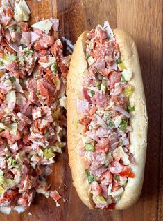 two hot dogs with toppings sitting on top of a wooden table