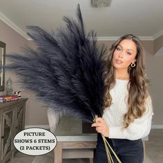 a woman holding a large black feather in her hand