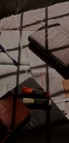 two books are sitting on a table next to some pens and pencils in front of them