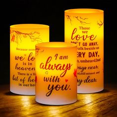 three lit candles with words on them sitting on top of a wooden table next to each other