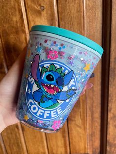 someone holding up a cup with the character stitching on it and sprinkles