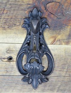 an ornate iron door handle on a wooden wall with wood planks in the background