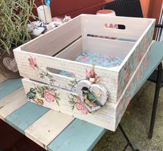 a wooden box sitting on top of a blue table next to a potted plant