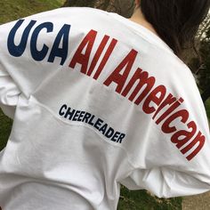 "UCA all American across the shoulders of this oversized jersey shirt and cheerleader in smaller letters under that line. This one has the British flag with name and year but it's your choice. Add matching bow! These run HUGE! The XS is about 42\" chest, S 44\" and so on. Order accordingly. Long sleeve, ring-spun cotton tshirt. Super soft . Please specify your lettering and colors allow 7-10 days processing." Sporty Letter Print Tops For Tailgating, Team Spirit Crew Neck Top For Tailgating, Team Spirit Tops For Tailgating With Crew Neck, Team Spirit Tops For Tailgating, Team Spirit Tops With Team Name For Tailgating, Tailgating Team Spirit Crew Neck Tops, Sporty Tops For College Events In Fall, Team Spirit Tops For Sports Season Tailgating, School Spirit T-shirt For Cheerleading In Fall