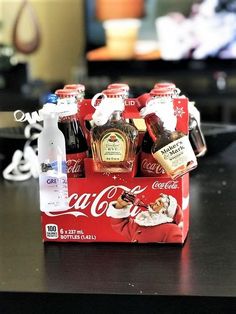 coca - cola bottles are sitting in a red box on a table next to a christmas ornament