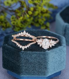 two wedding rings sitting on top of each other in a blue velvet box with green plants behind them