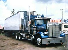 a blue semi truck parked in front of a building