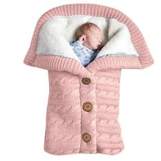 a baby wrapped in a pink sweater with buttons on the front and bottom, is shown