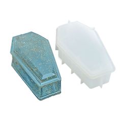 two pieces of blue and gold glittered plastic storage containers, one in the shape of a casket