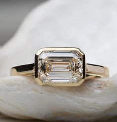 a close up of a diamond ring on top of a rock with shells in the background