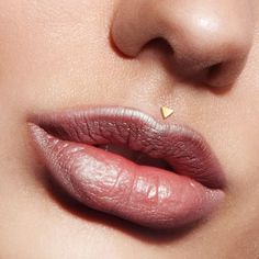 a woman's lips with a tiny gold triangle on her nose and the tip of her lip