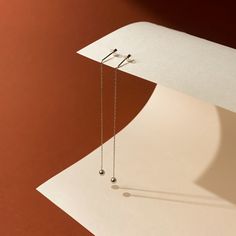 a pair of earrings hanging from the side of a piece of paper on a table