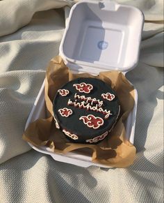 a birthday cake in a box on a bed