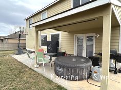 a hot tub sitting on top of a patio next to a house with an awning