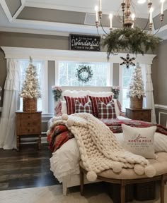 a bedroom decorated for christmas with plaid bedding and pillows, wreaths on the window sill