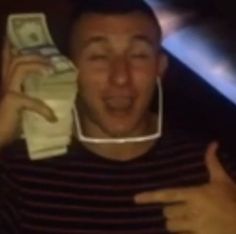 a man holding up a cell phone to his face with money in front of him