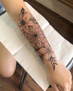 a woman's arm with flowers and leaves on the top half of her arm