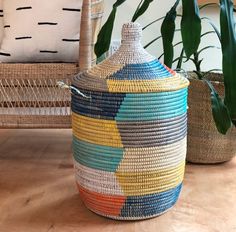 a woven basket sitting on top of a wooden floor next to a potted plant