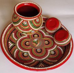 a red and green decorative vase sitting on top of a plate