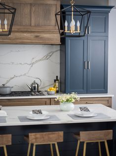 a kitchen with blue cabinets and marble counter tops, gold accents on the island top