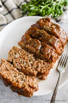 sliced meatloaf on a white plate with a fork and parsley in the background