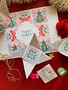 an origami christmas card surrounded by other holiday decorations and ornaments on a red background