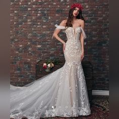 a woman in a wedding dress standing next to a brick wall with flowers on her head