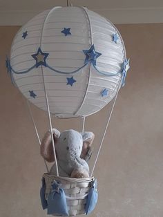 a stuffed elephant in a basket with blue stars on the sides and an air balloon attached to it