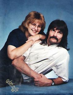 a man and woman are posing for a photo with a cat on their lap while holding each other