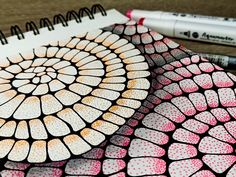 two markers are sitting on top of a drawing book with an intricate design in the middle