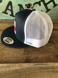 a black and white trucker hat sitting on top of a wooden table next to a sign