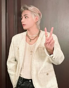 a person standing in front of a door making the peace sign with their hand and wearing a white jacket