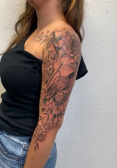 a woman with a tattoo on her arm and shoulder is standing in front of a white wall