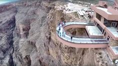 an aerial view of people walking on a glass walkway in the mountains above a city