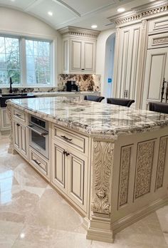 a large kitchen with marble counter tops and white cabinetry, along with an island in the middle