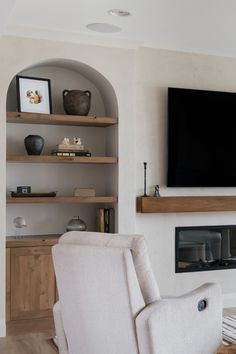 a large flat screen tv mounted on the wall above a fireplace in a living room