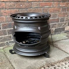 an old fashioned stove is sitting on the sidewalk next to a brick wall with a hole in it