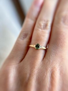 a woman's hand with a green ring on top of her finger and an emerald stone in the middle