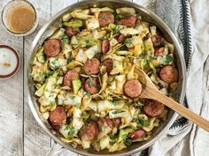 a pan filled with sausage, cabbage and noodles