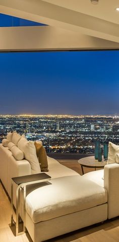 a living room filled with furniture next to a large window overlooking the city at night