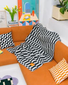 a living room with an orange couch and colorful art on the wall behind it,