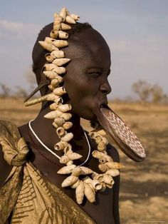 an african woman with corn husks on her head and necklace in the desert