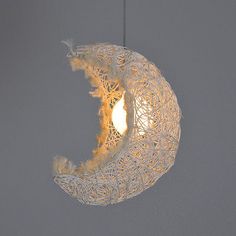 a white light hanging from the ceiling in front of a gray wall with a moon on it