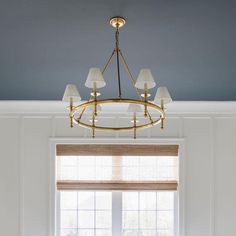 a chandelier hanging from the ceiling in a living room with blue walls and windows