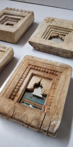 four pieces of carved wood sitting on top of a white table next to each other