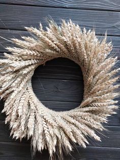 a wreath made out of dried grass sitting on top of a wooden wall