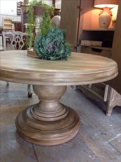 a large wooden table sitting on top of a floor next to a vase with flowers