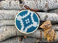 a blue and white cross stitched ornament sitting on top of tree branches