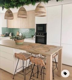 an island in the middle of a kitchen with wicker stools and baskets on it